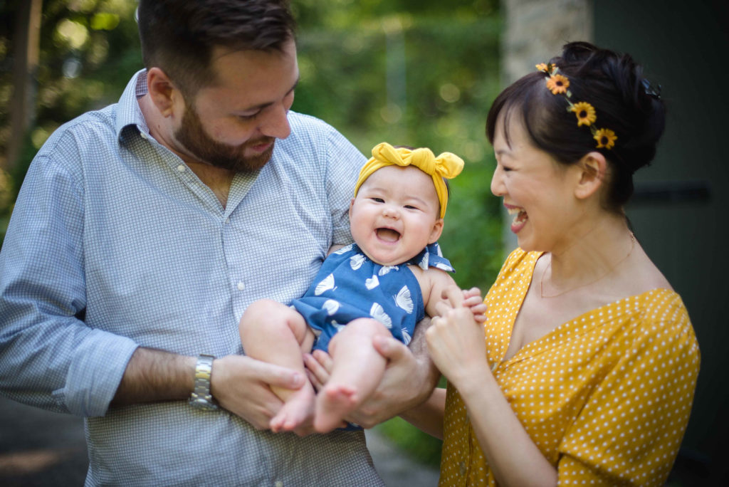 Parents holding giggling baby girl in Wissahickon Creek Park
