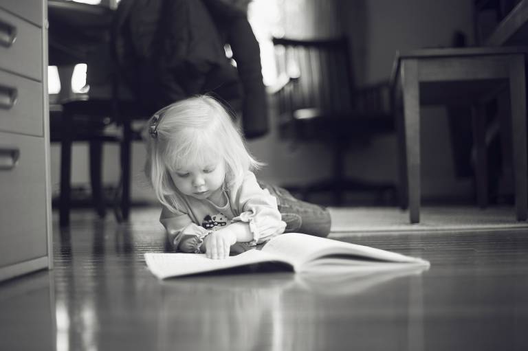 Little girl reading on floor