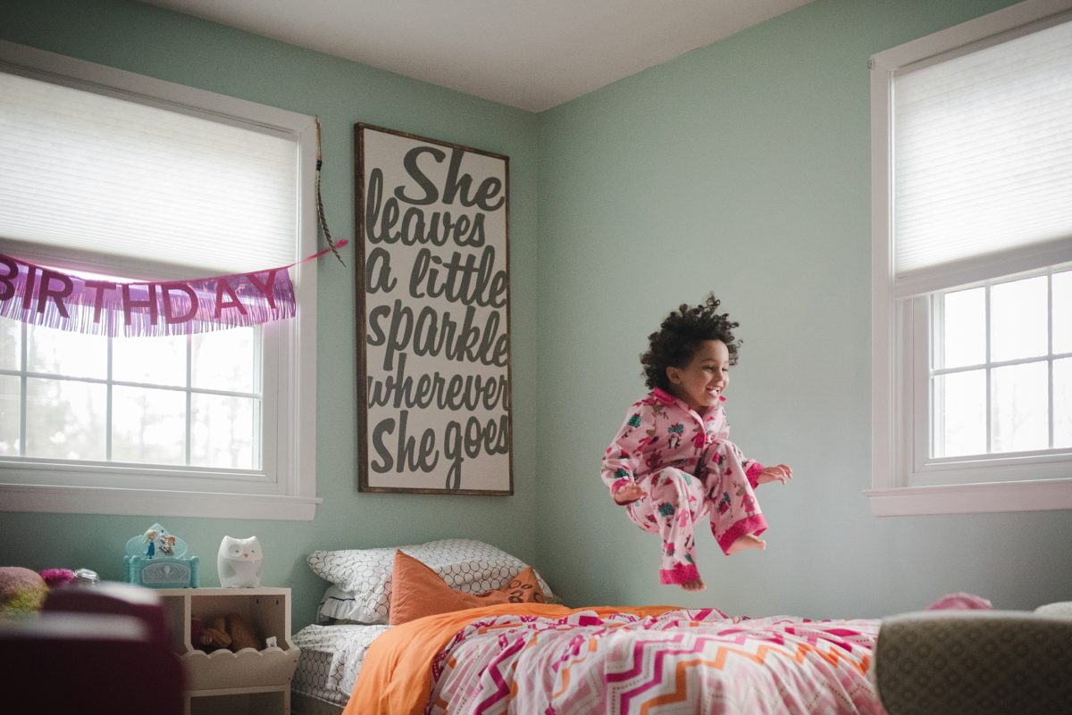 Little girl jumping on bed