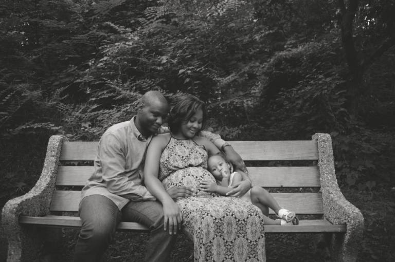 Family of three snuggling on a bench